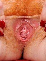 Naughty milf Sasha Brand strips off her clothes and fondles her red haired Anilos pussy on the sofa